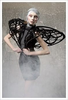 a woman in a black dress with wings on her head and hands behind her back