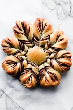 a pastry with chocolate swirls in the middle on top of white paper next to a marble countertop