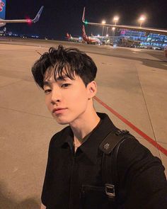 a young man standing on an airport tarmac at night