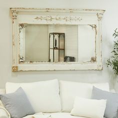 a white couch sitting under a mirror in a living room