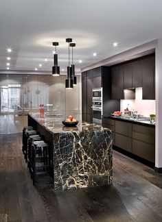 a modern kitchen with marble counter tops and black cabinets