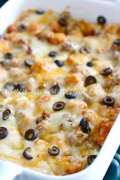 a casserole dish with cheese and black olives on the top, ready to be eaten