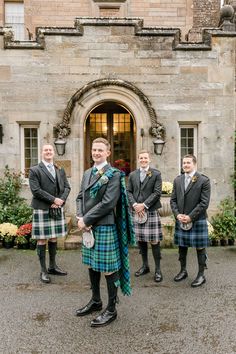 a group of men in kilts standing next to each other near a stone building