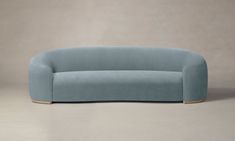 a blue couch sitting on top of a floor next to a gray wall with a wooden base