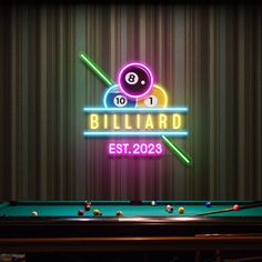 billiard neon sign on wall next to pool table with cues and ball in foreground