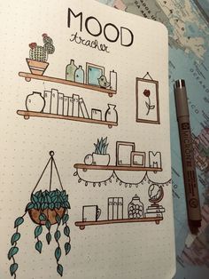 an open notebook with drawings on it and a pen in front of the book shelf