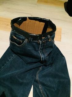 an empty pair of jeans sitting on top of a wooden floor