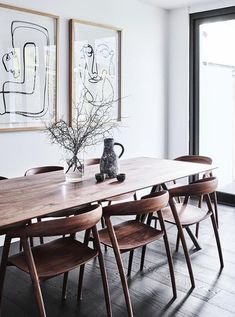 a dining room table with chairs and artwork on the wall