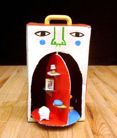 an open cardboard box with a red surfboard in it on a wooden table next to a black background