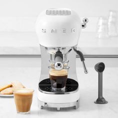 an espresso machine sitting on top of a counter next to a cup of coffee