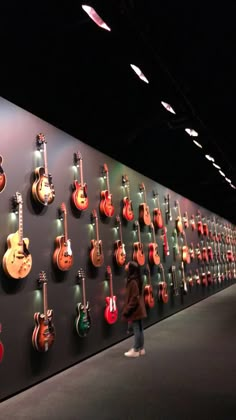 a person standing in front of a wall with guitars on it