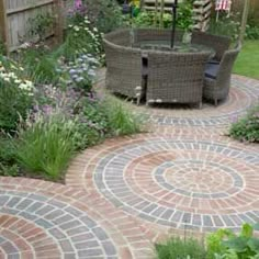 a brick patio with an umbrella in the center and flowers around it on either side