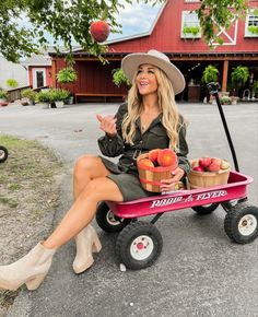 a woman is sitting on a wagon with apples in it and she's smiling