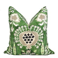 a green pillow with white and black flowers on the front, sitting on a white surface