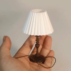 a hand holding a small lamp in the palm of a person's left hand