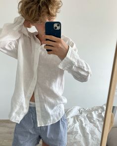 a person taking a selfie in front of a mirror while wearing shorts and a white shirt