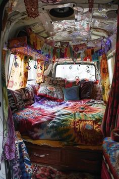 a bed in the back of a van with colorful bedspreads and curtains on it