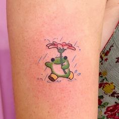 a small tattoo on the leg of a woman with a flower in it's hand