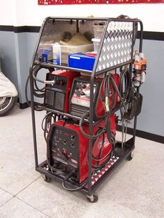 a red and black work station on wheels in a room with other vehicles behind it