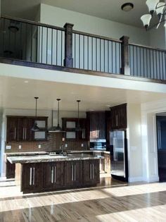 an empty kitchen and living room in a house with wood floors, white walls and railings