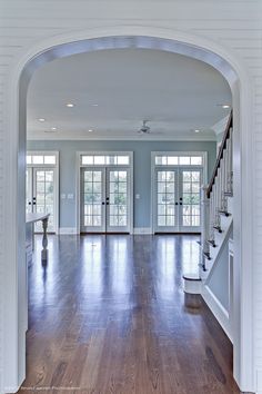 an archway leads to the living room and dining room in this house with hardwood floors