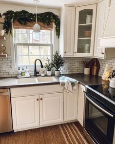 a kitchen with white cabinets, black counters and stainless steel stove top oven in it