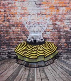 a white chair sitting on top of a wooden floor in front of a brick wall