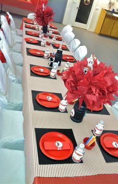 the table is set with red and black plates, napkins, and centerpieces