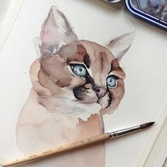 a watercolor painting of a cat with blue eyes and a pencil next to it