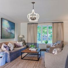 a living room filled with furniture and a chandelier hanging over it's windows