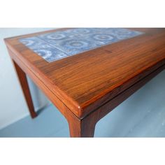 a close up of a wooden table with tile on the top and bottom part of it