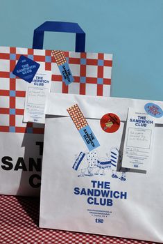 two paper bags sitting on top of a red and white checkered cloth covered table