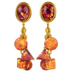 Kenzo Paris designed these stunning dangling clip-on earrings in the 1990s. The pieces feature a long dangle-drop cascading shape with a worked gilt metal chain complimented with resin geometric elements. The resin elements boast a lovely dark cantaloupe orange color with a yellow and dark red spotted pattern. One earring is marked on the underside Kenzo - Paris. Measurements: 1 in wide (2.6 cm) x 4.09 in long (10.4 cm). Kenzo Paris, Geometric Elements, One Earring, Paris Design, Clip Earrings, Metal Chain, Dark Red, Clip On Earrings, Orange Color