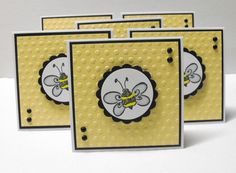 four yellow cards with black and white designs on them, one has a bee in the center