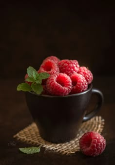 some raspberries in a black bowl on a table