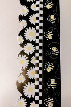 the back side of a skateboard with bees and daisies on black and white checkerboard