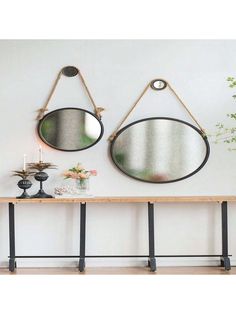 two mirrors hanging on the wall above a table