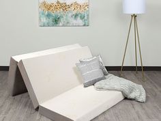 a white couch sitting on top of a hard wood floor next to a lamp and painting