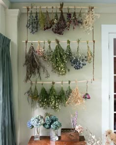 dried flowers are hung on the wall above a table