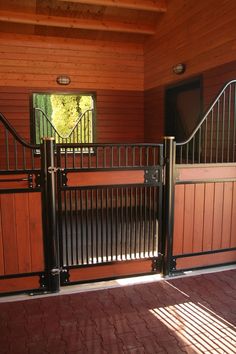 an open gate is shown in front of a wooden building with brick floors and walls