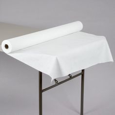 a roll of white paper sitting on top of a metal table with a cloth draped over it