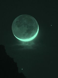 the moon is glowing green in the night sky