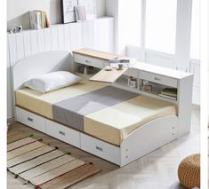 a white bed with drawers underneath it in a room next to a rug and window