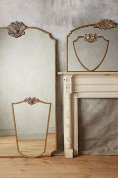 two mirrors sitting next to each other on top of a wooden floor near a fireplace