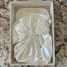 an open box with a white satin bow on the front and back of it, sitting on a marble surface