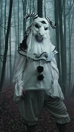 a man dressed up as a white wolf in the middle of a forest with trees