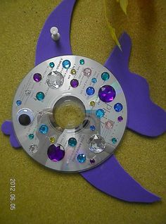 a metal clock with purple and blue jewels on it's face sitting on the floor