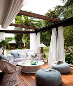 an outdoor living room with white furniture and curtains