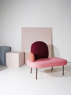 a pink and red chair sitting in front of a white wall next to two boxes