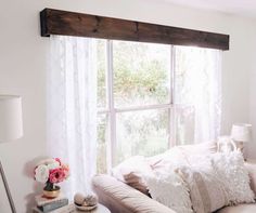 a living room filled with furniture and a large window covered in white curtained drapes